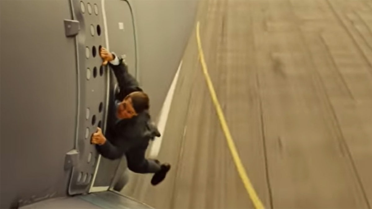 Tom Cruise hanging off a plane during a stunt for Mission Impossible