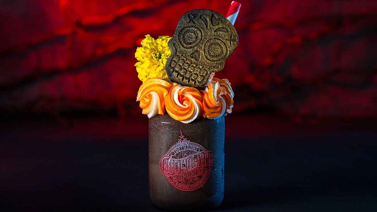 A milkshake topped with a skull cookie.